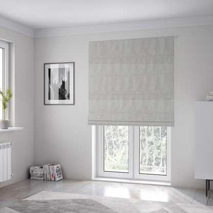 The fabric used to create these Roman blinds is a light oatmeal or pearl grey textile featuring a tight diagonal twill weave. The fabric is a multi-tonal blend, interlacing crisp white and pale grey yarns with subtle flecks of soft gold and charcoal, creating a luminous, heathered appearance.