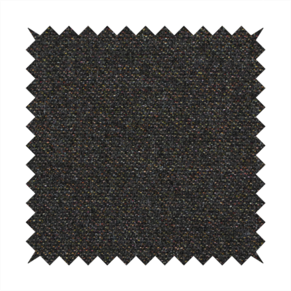 A near-black charcoal base heavily flecked with multi-coloured yarns in gold, rust, and grey.