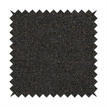 A near-black charcoal base heavily flecked with multi-coloured yarns in gold, rust, and grey.