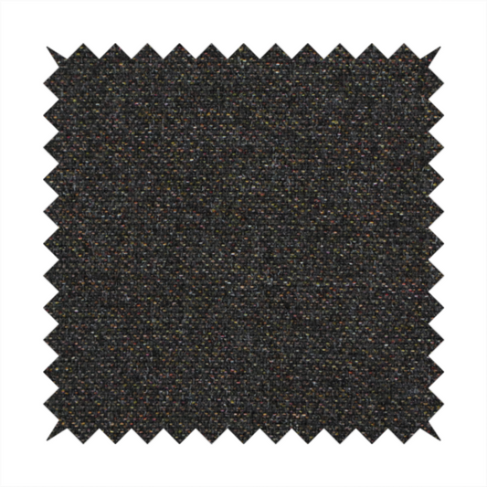 A near-black charcoal base heavily flecked with multi-coloured yarns in gold, rust, and grey.