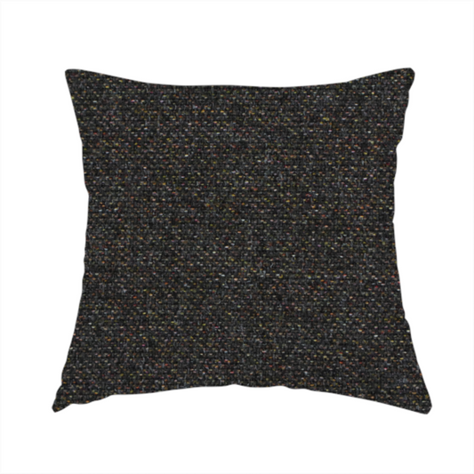 The fabric used to create this handmade cushion is a near-black charcoal base heavily flecked with multi-coloured yarns in gold, rust, and grey.