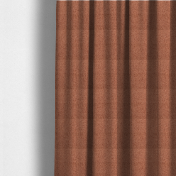The fabric used to create these made-to-measure curtains is a rust-orange upholstery fabric with a dense, diagonal textured weave.