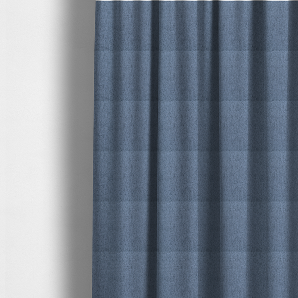 The fabric used to create these made-to-measure curtains is a mid-blue upholstery fabric with a dense, diagonal textured weave.