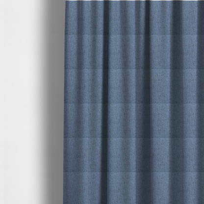 The fabric used to create these made-to-measure curtains is a mid-blue upholstery fabric with a dense, diagonal textured weave.