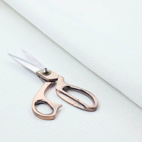 A solid white fabric with a distinct, tightly woven grid texture. The material features a uniform, grid-like pattern of tiny raised squares, reminiscent of Aida cloth or a textured linen blend, creating a subtle, clean, and matte finish across the entire surface.