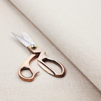 A cream or off-white fabric featuring a distinct, tightly woven grid texture. The material has a uniform, basket-weave style pattern with subtle variations in tone, creating a soft, warm, and matte finish across the entire surface.