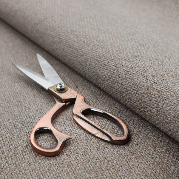 A taupe or light greyish-brown fabric featuring a distinct, tightly woven grid texture. The material showcases a multi-tonal, basket-weave style pattern with blending neutral threads, creating a soft, heathered, and matte finish across the entire surface.