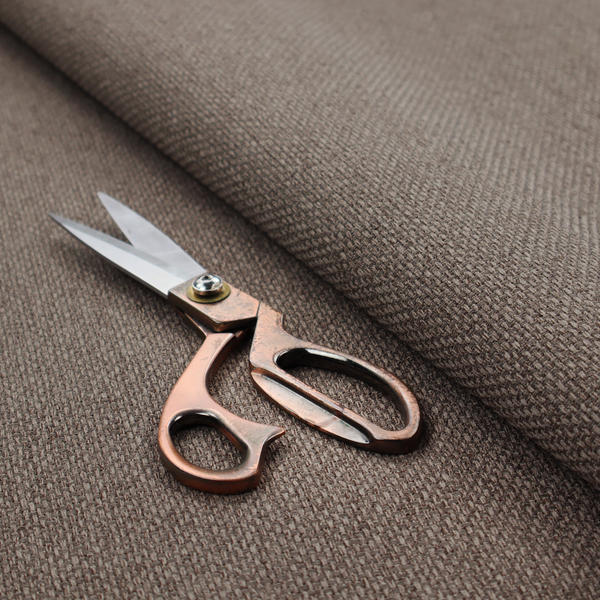 A medium brown or mocha fabric featuring a distinct, tightly woven grid texture. The material showcases a multi-tonal, basket-weave style pattern with interlaced neutral and earthy threads, creating a rich, textured, and matte finish across the entire surface.