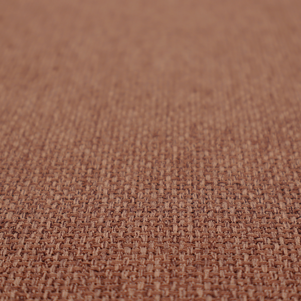 A rust or terracotta-brown fabric featuring a distinct, tightly woven grid texture. The material showcases a multi-tonal, basket-weave style pattern with interlaced copper and warm brown threads, creating a rich, earthy, and matte finish across the entire surface.