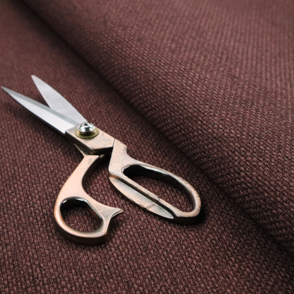 A deep maroon or burgundy fabric featuring a distinct, tightly woven grid texture. The material showcases a rich, multi-tonal, basket-weave style pattern with interlaced plum and dark earthy threads, creating a warm, elegant, and matte finish across the entire surface.