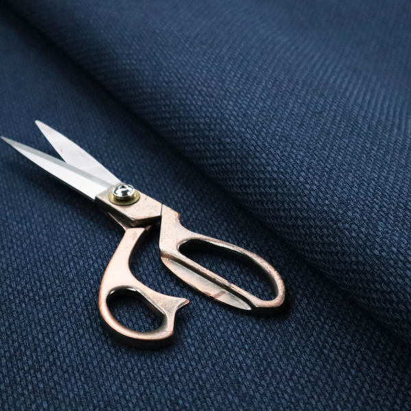 A deep navy or indigo blue fabric featuring a distinct, tightly woven grid texture. The material showcases a multi-tonal, basket-weave style pattern with blended dark blue and subtle charcoal threads, creating a rich, classic, and matte finish across the entire surface.
