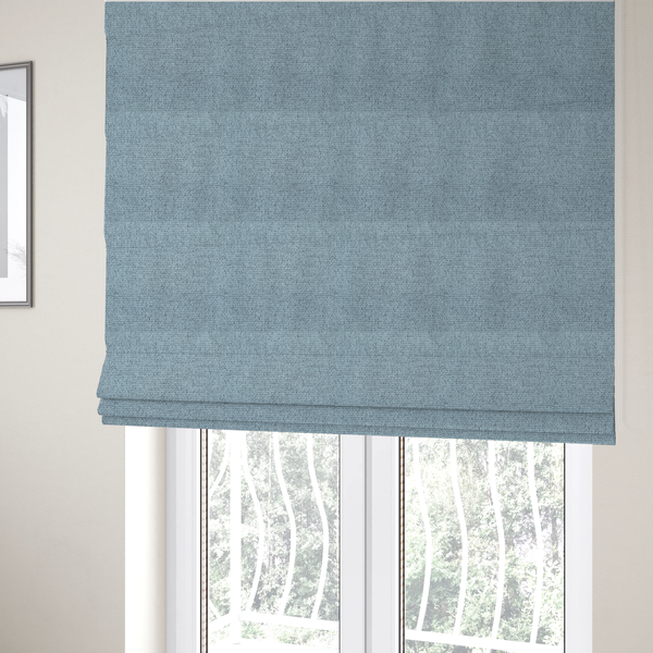 The fabric used to create these Roman blinds is a light ice blue or pastel blue fabric featuring a distinct, tightly woven grid texture. The material showcases a multi-tonal, basket-weave style pattern with blended sky blue and subtle grey threads, creating a fresh, serene, and matte finish across the entire surface.