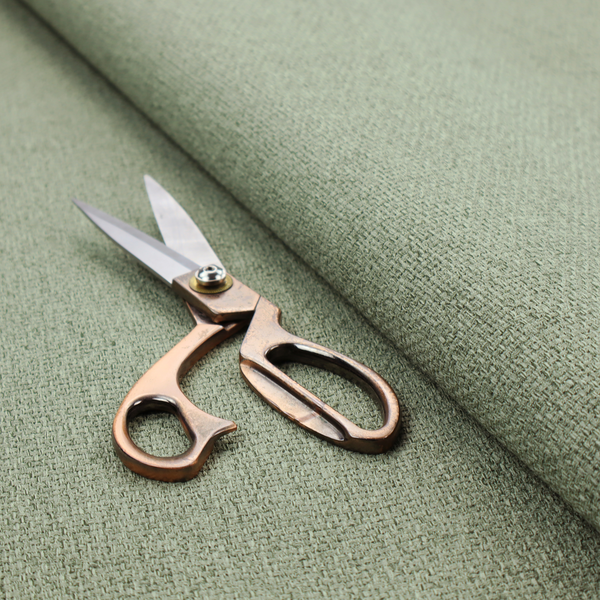 A light sage or mint green fabric featuring a distinct, tightly woven grid texture. The material showcases a multi-tonal, basket-weave style pattern with blended pale green and subtle grey threads, creating a fresh, calming, and matte finish across the entire surface.