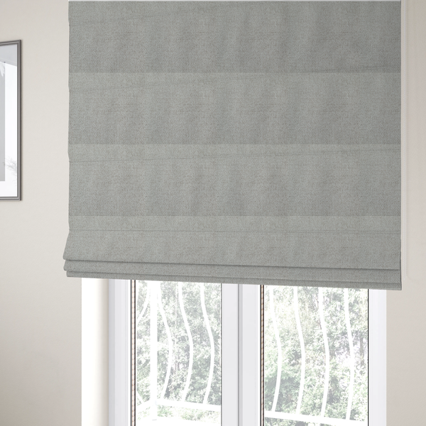 The fabric used to create these Roman blinds is a light silver-grey or ash-grey fabric featuring a distinct, tightly woven grid texture. The material showcases a multi-tonal, basket-weave style pattern with blended cool grey and subtle pale threads, creating a clean, neutral, and matte finish across the entire surface.