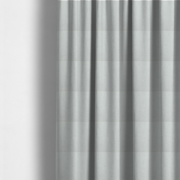The fabric used to create these made-to-measure curtains is a light grey or soft ash fabric featuring a distinct, tightly woven grid texture. The material showcases a multi-tonal, basket-weave style pattern with blended pale grey and subtle white threads, creating a clean, neutral, and matte finish across the entire surface.