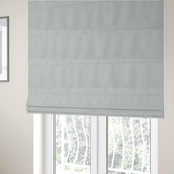 The fabric used to create these Roman blinds is a light grey or soft ash fabric featuring a distinct, tightly woven grid texture. The material showcases a multi-tonal, basket-weave style pattern with blended pale grey and subtle white threads, creating a clean, neutral, and matte finish across the entire surface.
