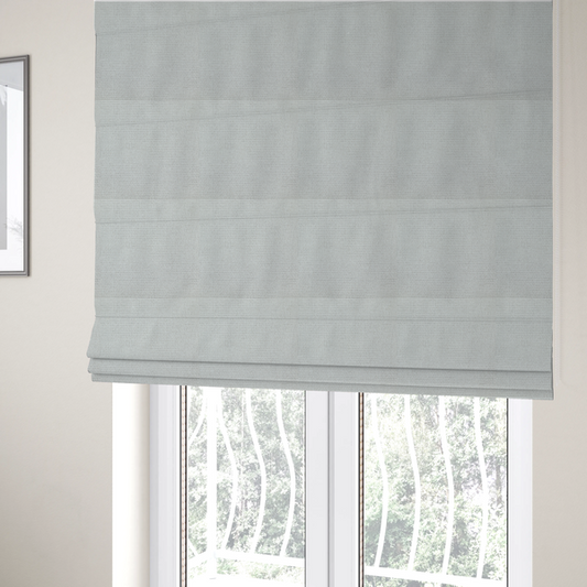 The fabric used to create these Roman blinds is a light grey or soft ash fabric featuring a distinct, tightly woven grid texture. The material showcases a multi-tonal, basket-weave style pattern with blended pale grey and subtle white threads, creating a clean, neutral, and matte finish across the entire surface.