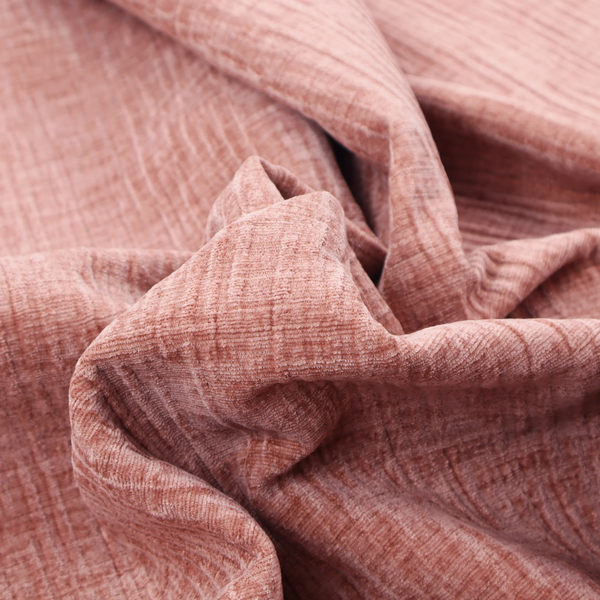 A textured upholstery fabric in a soft, light blush pink shade. The material features a distinctive cross-hatched slub texture with fine vertical and horizontal ridges, creating a plush, tactile chenille finish.