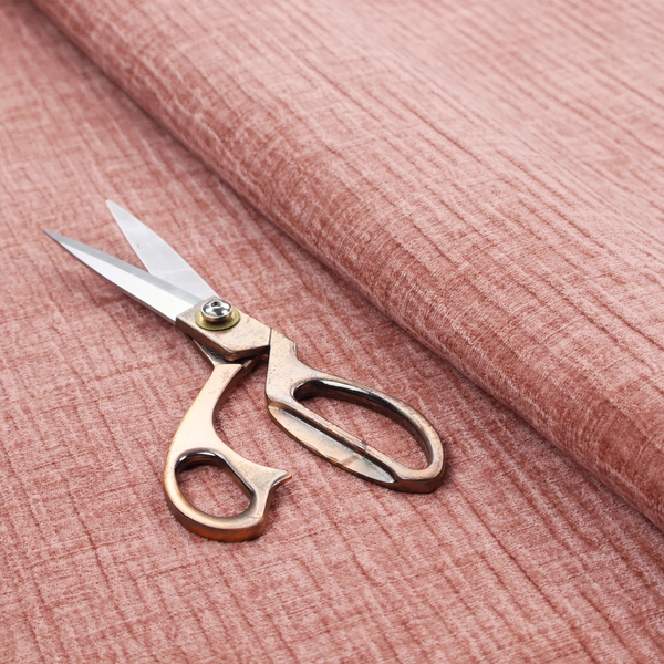 A textured upholstery fabric in a soft, light blush pink shade. The material features a distinctive cross-hatched slub texture with fine vertical and horizontal ridges, creating a plush, tactile chenille finish.