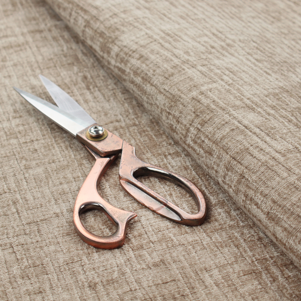 A textured upholstery fabric in a warm, neutral beige or oatmeal colour. The material features a distinct cross-hatched slub texture with fine vertical and horizontal ridges, creating a soft, dimensional chenille finish.