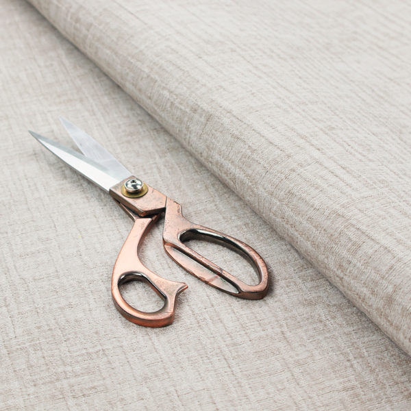 A textured upholstery fabric in a light cream or ivory colour. The material features a subtle cross-hatched slub texture with fine vertical and horizontal ridges, creating a soft, dimensional chenille finish.