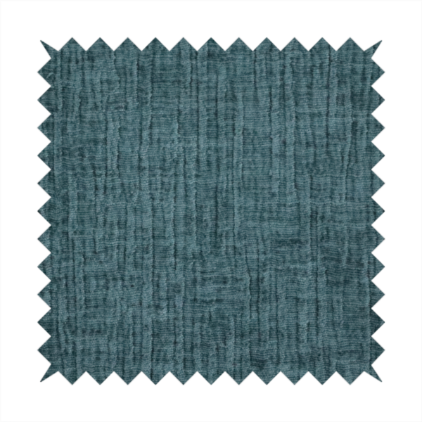 A textured upholstery fabric in a vibrant peacock blue or deep teal shade. The material features a distinct cross-hatched slub texture with prominent vertical and fine horizontal ridges, creating a soft, dimensional chenille finish.