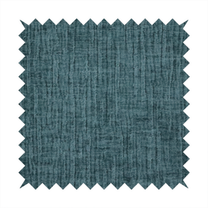 A textured upholstery fabric in a vibrant peacock blue or deep teal shade. The material features a distinct cross-hatched slub texture with prominent vertical and fine horizontal ridges, creating a soft, dimensional chenille finish.