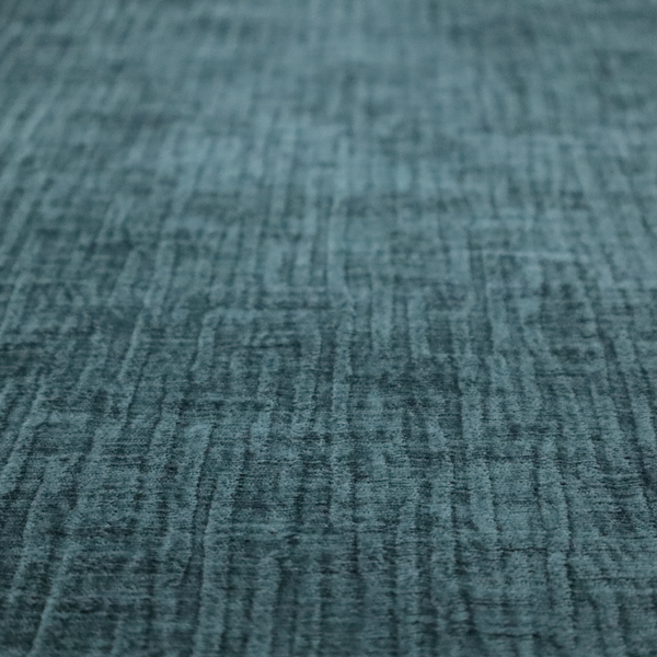 A textured upholstery fabric in a vibrant peacock blue or deep teal shade. The material features a distinct cross-hatched slub texture with prominent vertical and fine horizontal ridges, creating a soft, dimensional chenille finish.