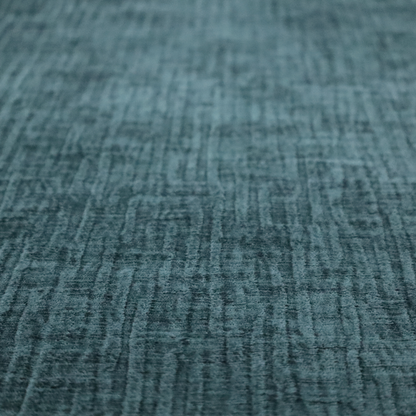 A textured upholstery fabric in a vibrant peacock blue or deep teal shade. The material features a distinct cross-hatched slub texture with prominent vertical and fine horizontal ridges, creating a soft, dimensional chenille finish.