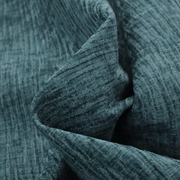 A textured upholstery fabric in a vibrant peacock blue or deep teal shade. The material features a distinct cross-hatched slub texture with prominent vertical and fine horizontal ridges, creating a soft, dimensional chenille finish.
