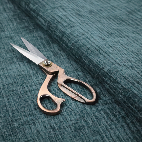 A textured upholstery fabric in a vibrant peacock blue or deep teal shade. The material features a distinct cross-hatched slub texture with prominent vertical and fine horizontal ridges, creating a soft, dimensional chenille finish.