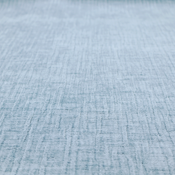 A textured upholstery fabric in a soft powder blue or light sky blue shade. The material features a distinct cross-hatched slub texture with subtle vertical and horizontal ridges, creating a soft, dimensional chenille finish.