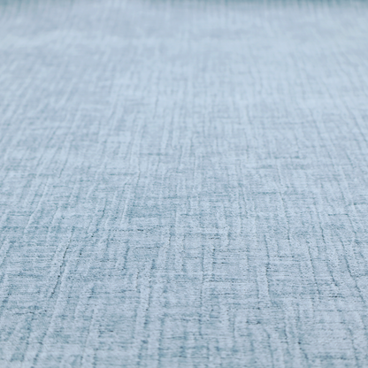 A textured upholstery fabric in a soft powder blue or light sky blue shade. The material features a distinct cross-hatched slub texture with subtle vertical and horizontal ridges, creating a soft, dimensional chenille finish.