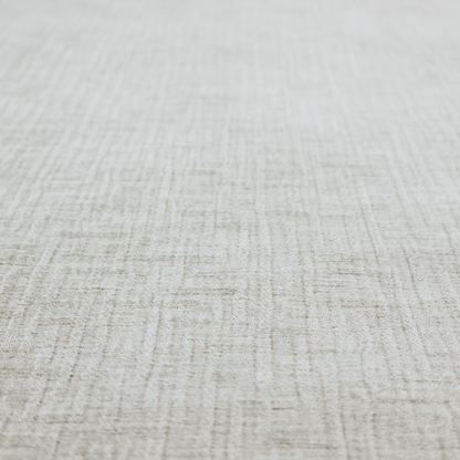 A textured upholstery fabric in a light silver or pale grey colour. The material features a subtle cross-hatched slub texture with fine vertical and horizontal ridges, creating a soft, dimensional chenille finish.