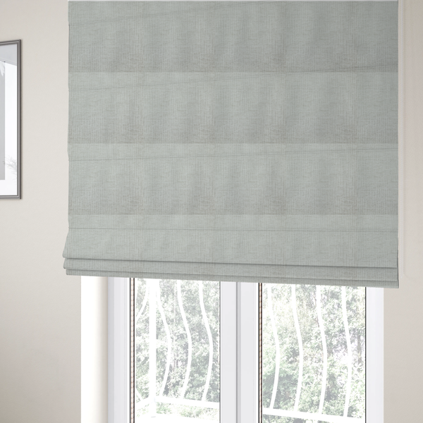 The fabric used to create these Roman blinds is a textured upholstery fabric in a light silver or pale grey colour. The material features a subtle cross-hatched slub texture with fine vertical and horizontal ridges, creating a soft, dimensional chenille finish.