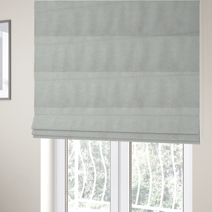 The fabric used to create these Roman blinds is a textured upholstery fabric in a light silver or pale grey colour. The material features a subtle cross-hatched slub texture with fine vertical and horizontal ridges, creating a soft, dimensional chenille finish.