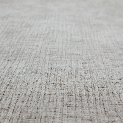 A textured upholstery fabric in a mid-tone grey or pebble shade. The material features a distinct cross-hatched slub texture with prominent vertical and fine horizontal ridges, creating a soft, dimensional chenille finish.