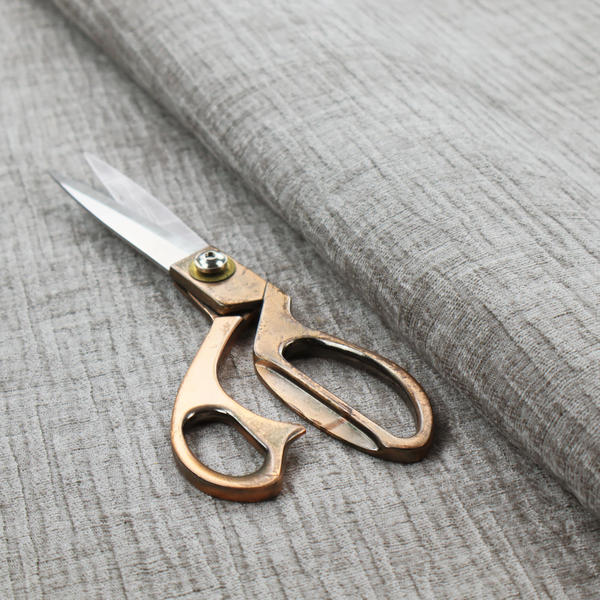 A textured upholstery fabric in a mid-tone grey or pebble shade. The material features a distinct cross-hatched slub texture with prominent vertical and fine horizontal ridges, creating a soft, dimensional chenille finish.