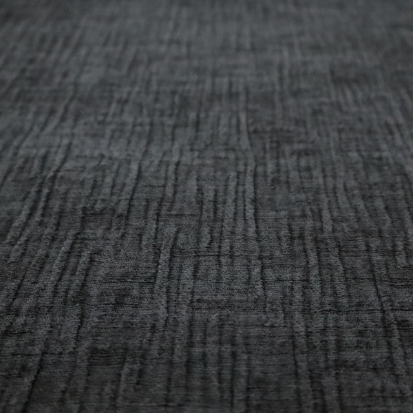 A textured upholstery fabric in a near-black or dark anthracite shade. The material features a distinct cross-hatched slub texture with prominent vertical and fine horizontal ridges, creating a soft, dimensional chenille finish.