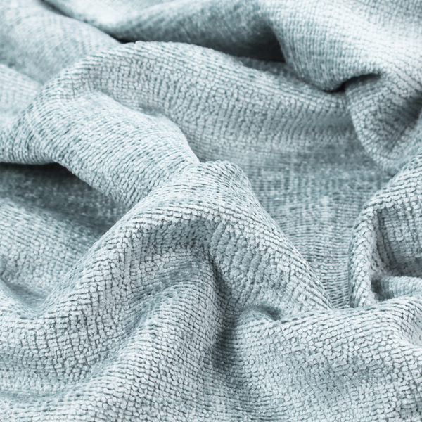 A textured fabric swatch in a soft, pale ice-blue colour. The material features a dense, uniform nubby weave or loop texture, resembling chenille, bouclé, or terry cloth, with subtle variations in shading that create a matte, soft appearance.