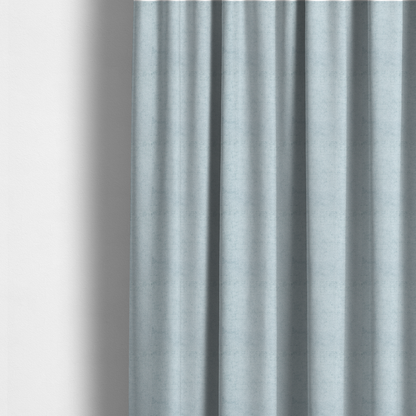 The fabric used to create these made-to-measure curtains is a textured fabric swatch in a soft, pale ice-blue colour. The material features a dense, uniform nubby weave or loop texture, resembling chenille, bouclé, or terry cloth, with subtle variations in shading that create a matte, soft appearance.