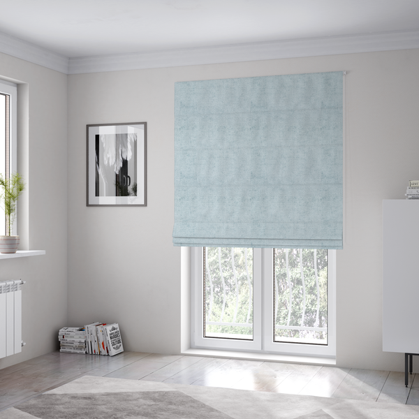The fabric used to create these Roman blinds is a textured fabric swatch in a soft, pale ice-blue colour. The material features a dense, uniform nubby weave or loop texture, resembling chenille, bouclé, or terry cloth, with subtle variations in shading that create a matte, soft appearance.