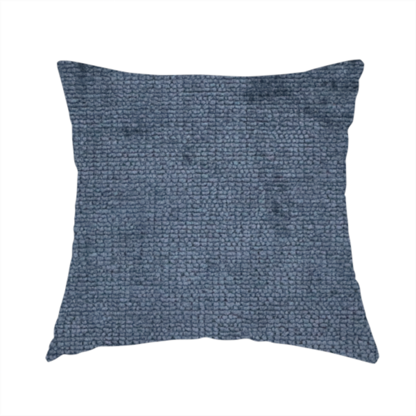 The fabric used to create this handmade cushion is a textured fabric swatch in a deep slate blue or denim colour. The material features a dense, uniform nubby weave with subtle dark mottling throughout, giving the soft, textured surface a multi-tonal appearance.