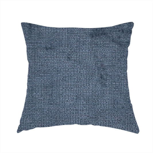The fabric used to create this handmade cushion is a textured fabric swatch in a deep slate blue or denim colour. The material features a dense, uniform nubby weave with subtle dark mottling throughout, giving the soft, textured surface a multi-tonal appearance.