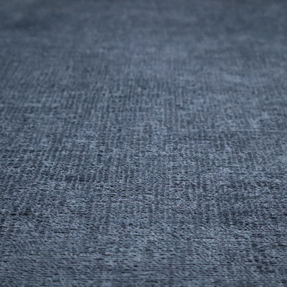 A textured fabric swatch in a deep slate blue or denim colour. The material features a dense, uniform nubby weave with subtle dark mottling throughout, giving the soft, textured surface a multi-tonal appearance.