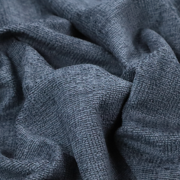 A textured fabric swatch in a deep slate blue or denim colour. The material features a dense, uniform nubby weave with subtle dark mottling throughout, giving the soft, textured surface a multi-tonal appearance.
