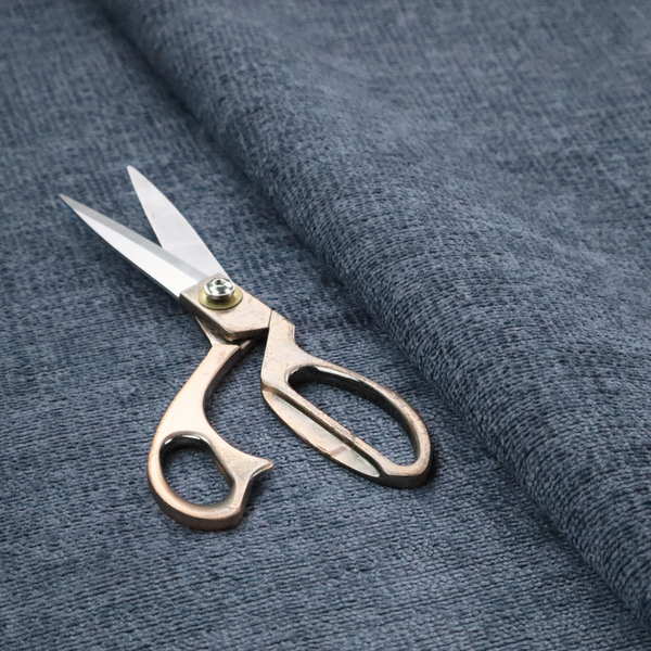 A textured fabric swatch in a deep slate blue or denim colour. The material features a dense, uniform nubby weave with subtle dark mottling throughout, giving the soft, textured surface a multi-tonal appearance.