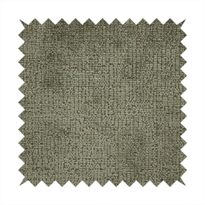 A textured fabric swatch in an earthy olive green or sage colour. The material features a dense, uniform nubby weave with subtle dark mottling throughout, giving the soft, textured surface a multi-tonal, organic appearance.