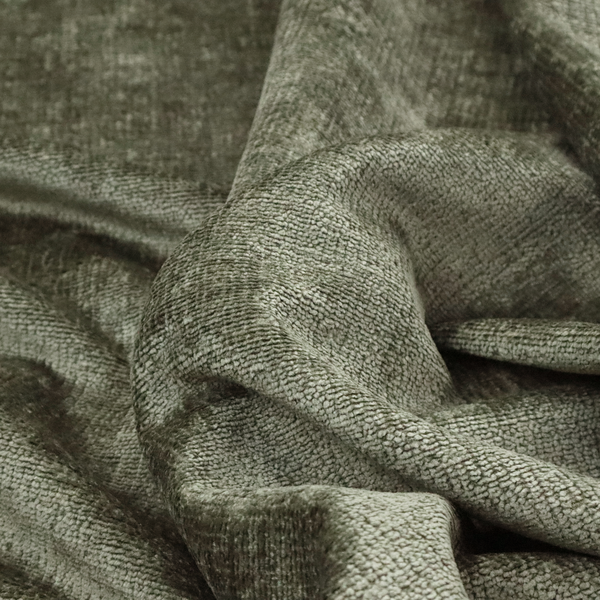 A textured fabric swatch in an earthy olive green or sage colour. The material features a dense, uniform nubby weave with subtle dark mottling throughout, giving the soft, textured surface a multi-tonal, organic appearance.