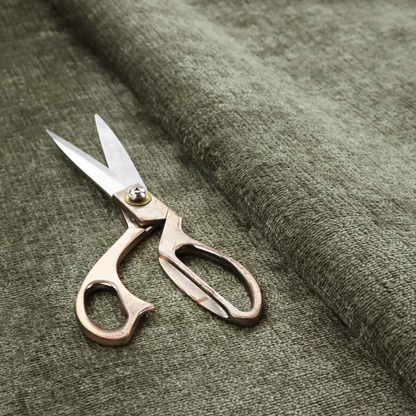 A textured fabric swatch in an earthy olive green or sage colour. The material features a dense, uniform nubby weave with subtle dark mottling throughout, giving the soft, textured surface a multi-tonal, organic appearance.